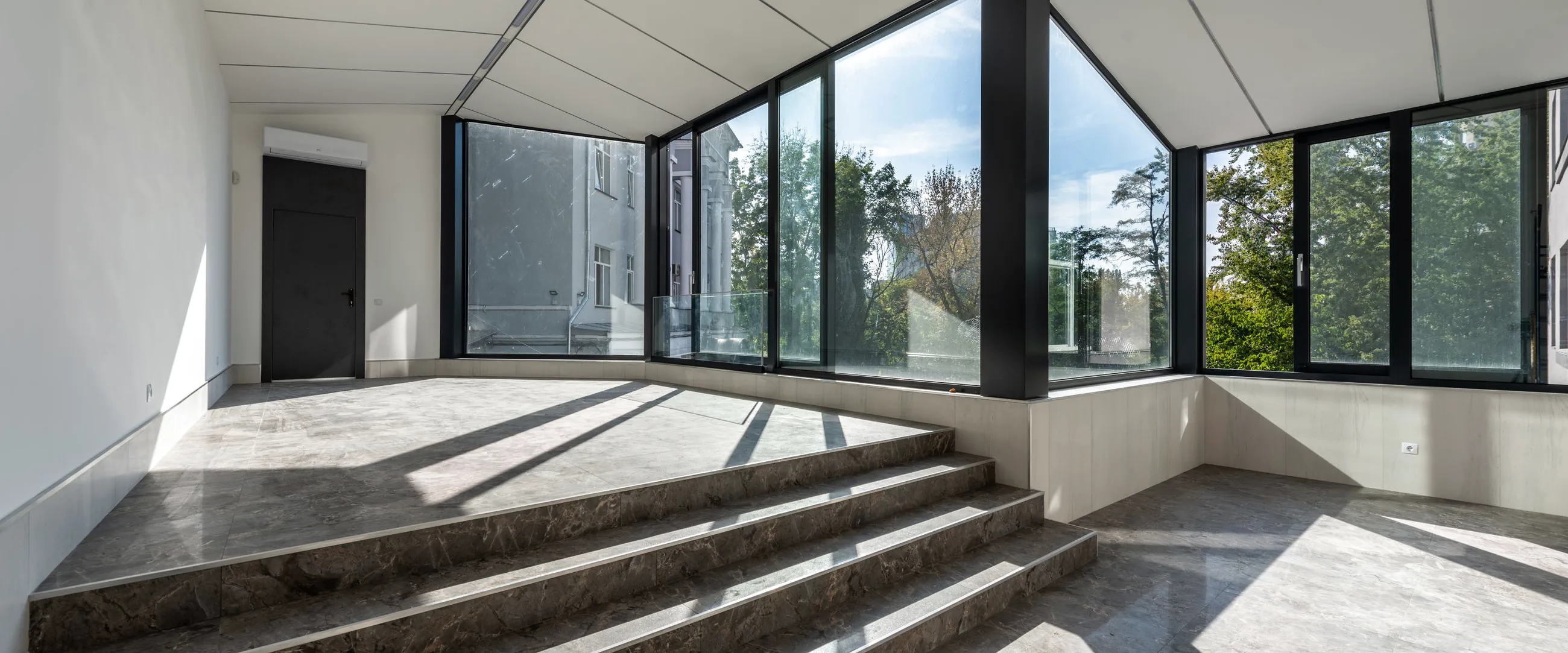 The stair hall of the new city library, a glazed wall and stone steps in flat daylight
