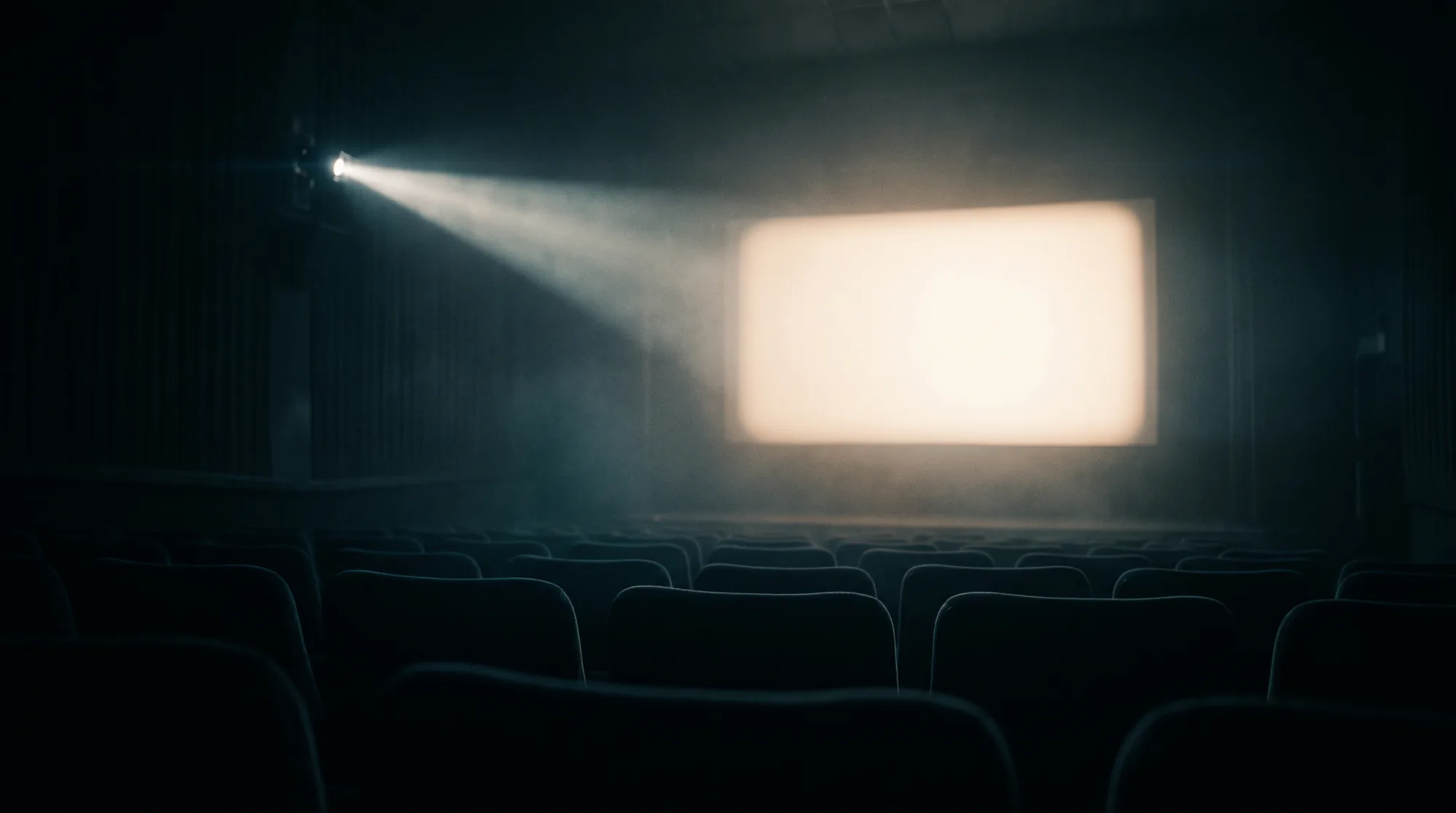 A projector beam cutting through haze toward a blank cinema screen