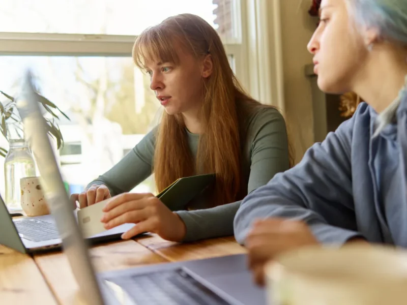 Two women working on laptops at a shared table